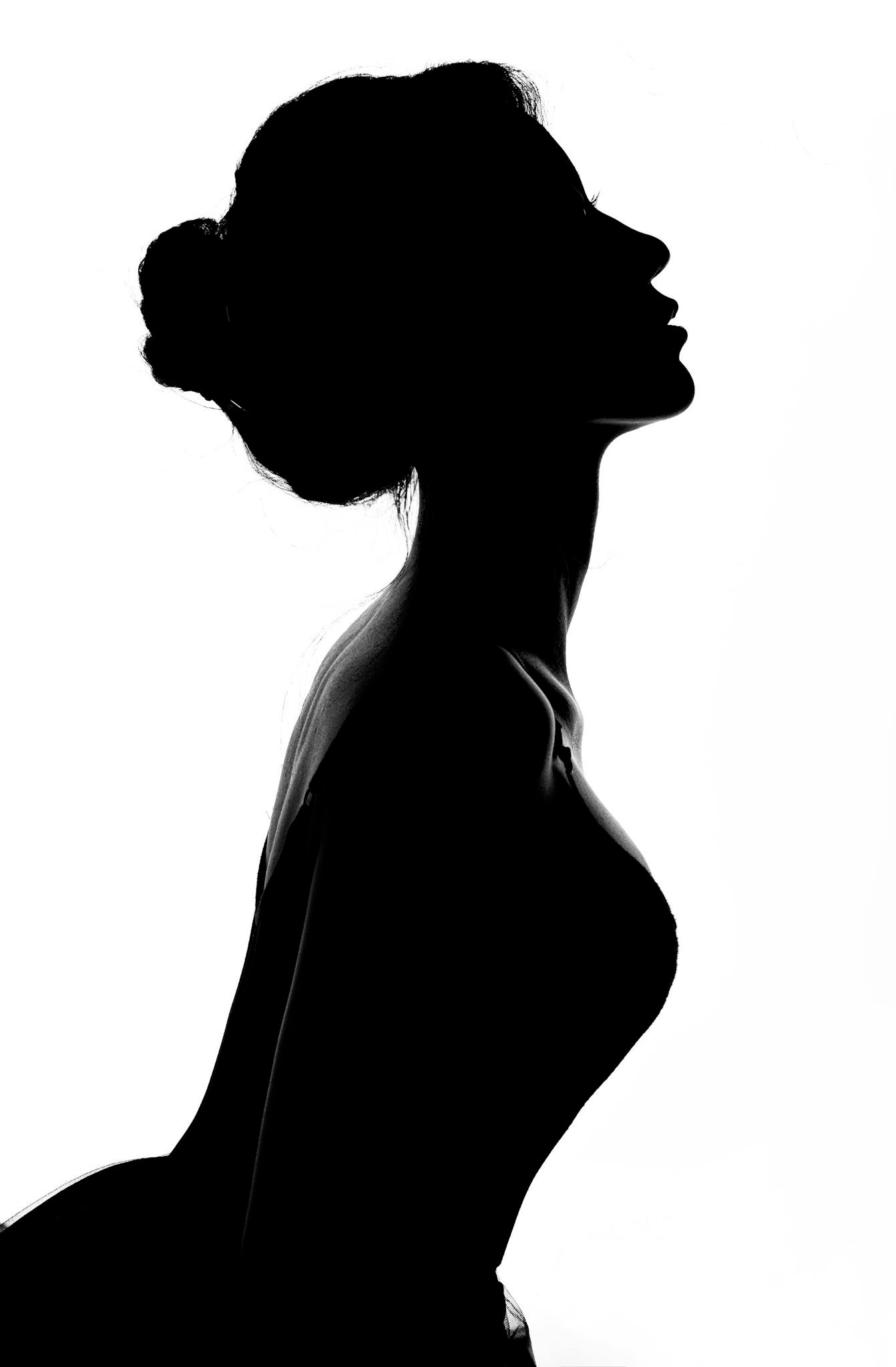 Dramatic black and white silhouette of a woman posing gracefully against a white background.