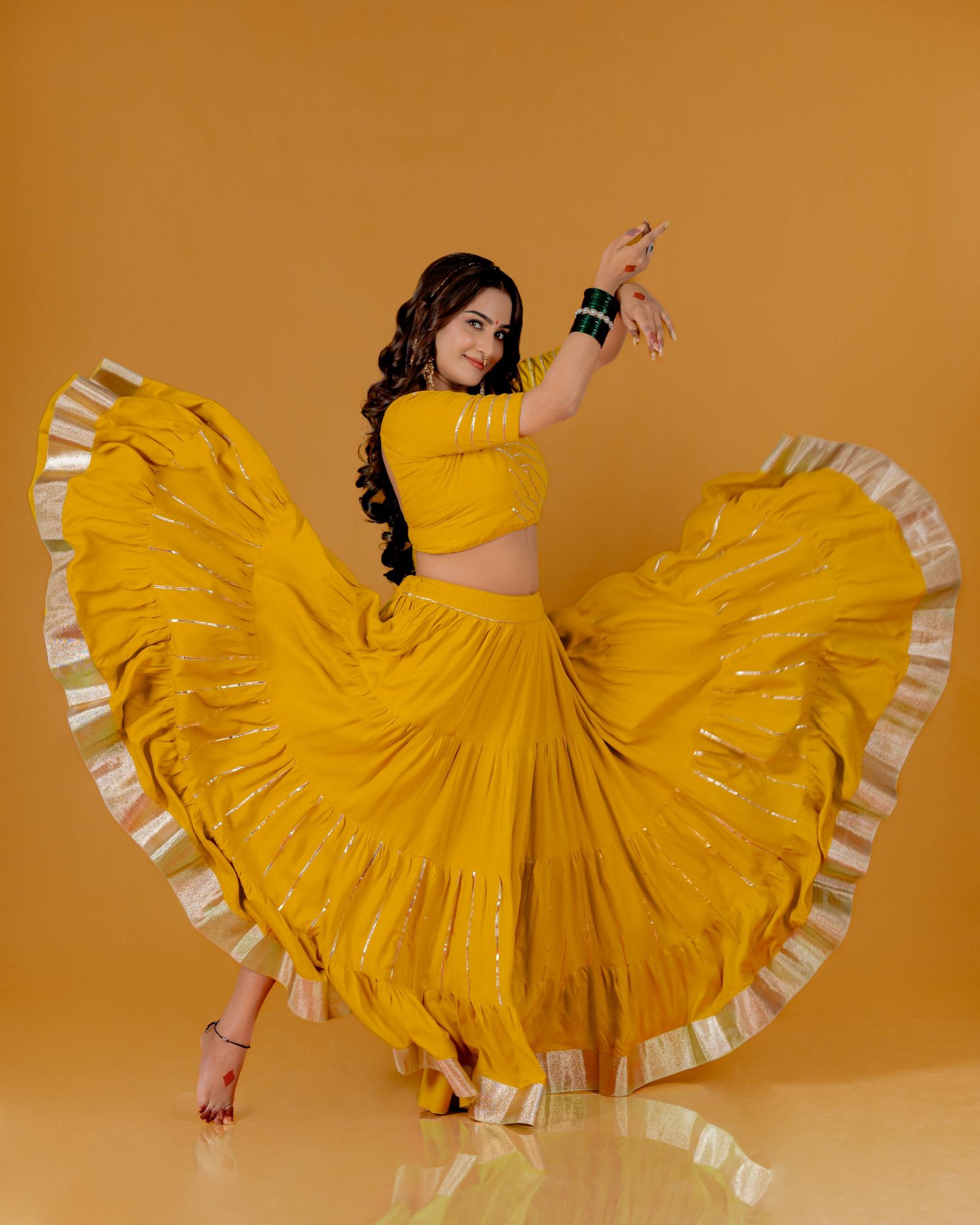 Woman performing a traditional Indian dance in a vibrant yellow outfit with a beautiful flow.